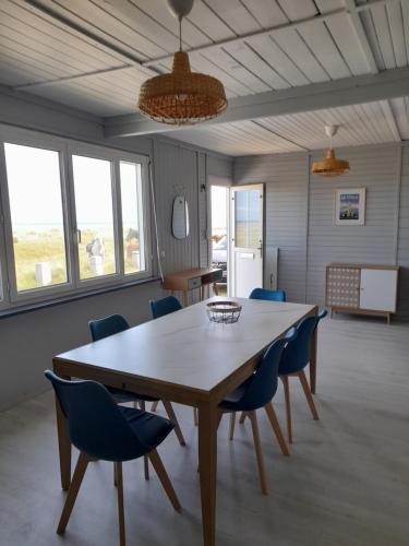 QuinévilleMaison les pieds dans la mer的一间带木桌和蓝色椅子的用餐室