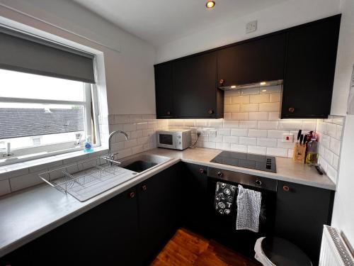 伦弗鲁Renfrew Home from Home的厨房配有黑色橱柜、水槽和窗户。