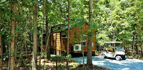 Boiling SpringsBroad River Campground Cabins & Domes的树林里有一辆车的高尔夫球车的小房子