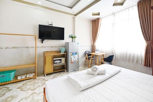 胡志明市Huyen House的一间卧室配有一张床、一台电视和一张桌子