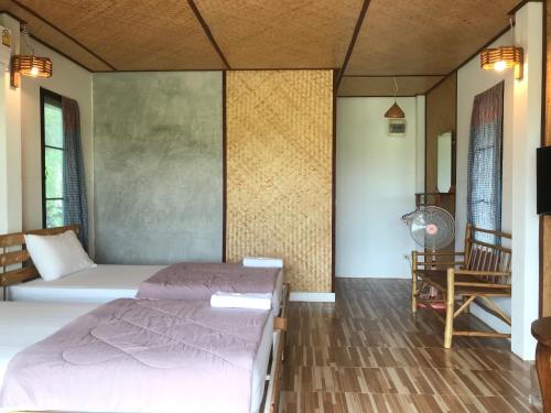 乌泰他尼府บ้านกลางเกาะ รีสอร์ท的一间卧室配有两张床、一张桌子和一台电视。