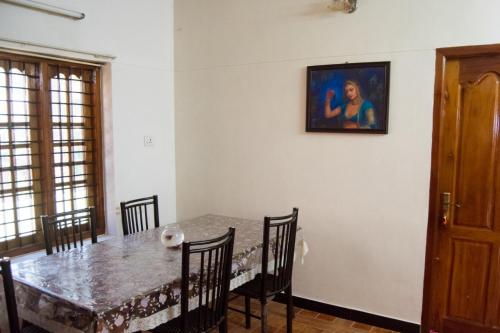 特里凡得琅Texas Guest house的餐桌、椅子和墙上的绘画