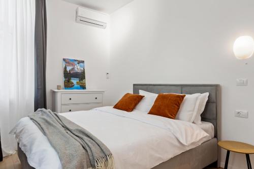 布加勒斯特VD Boutique Apartments No 1 Bucharest的一间卧室配有带白色床单和橙色枕头的床。