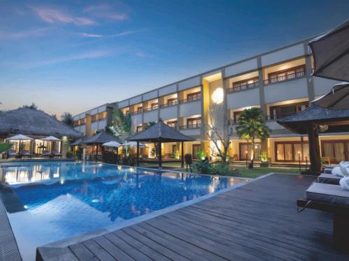 龙目岛库塔Sima Hotel Kuta Lombok的夜间设有游泳池的酒店