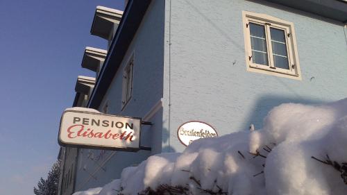萨尔茨堡Pension Elisabeth - Rooms & Apartments的一座有标志和一堆积雪的建筑