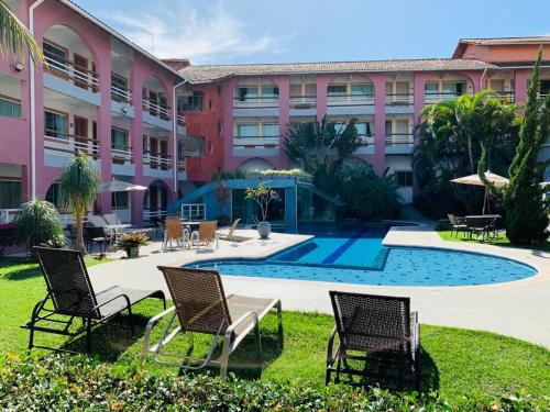 马卡埃Brisa da Costa Suites的一个带游泳池和椅子的度假胜地和一座建筑