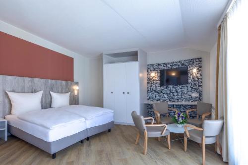 诺德奈Michels Gästehaus Meerzeit的酒店客房带一张床、一张桌子和椅子