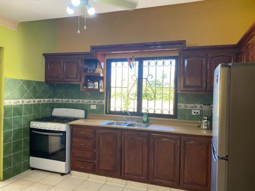 拉罗马纳Villa Victoria的厨房配有木制橱柜、水槽和窗户。