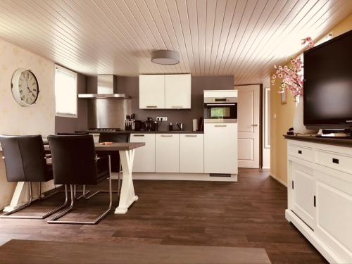 福尔特赫伊曾Vakantiehuis “Het Zeepaard”的厨房配有白色橱柜和桌椅