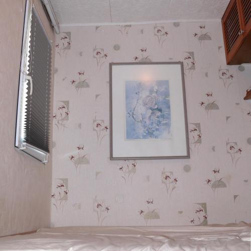 KrauschwitzBungalow im Märchengarten的卧室配有花卉壁纸和墙上的照片
