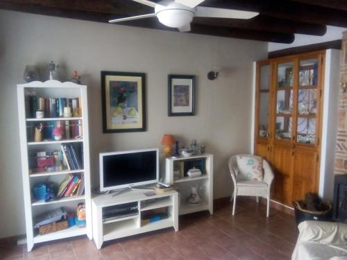 莱图尔Casa Rural la Escalera的一间带电视和白色书架的客厅