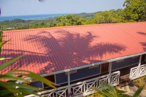 Six HutsCoco Bahia Apartment的一座红色屋顶的建筑,上面有棕榈树