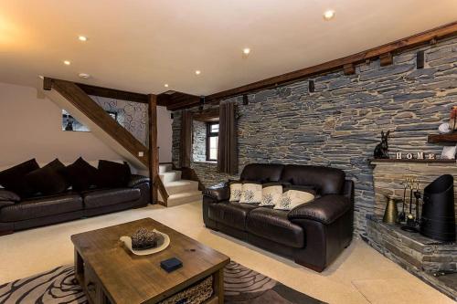 MenheniotLuxurious Self Catering Holiday Cottage Cornwall的客厅设有真皮沙发和石墙