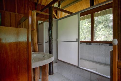 马尔多纳多港Ecoamazonia Lodge的一间带水槽和浴缸的浴室以及窗户。