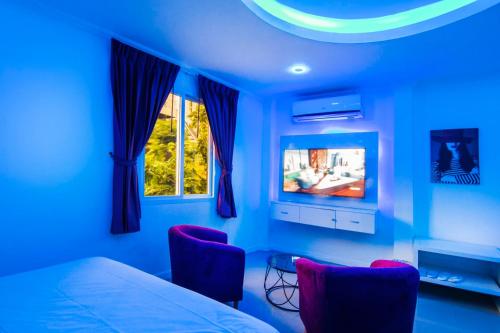 芭堤雅市中心titanic residence的一间蓝色的卧室,配有一张床和一台电视