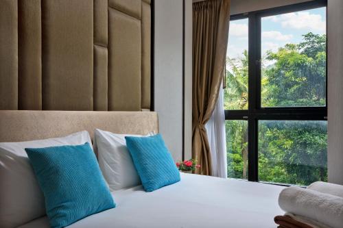 苏林海滩Panora Surin by Holy Cow, 1-BR, mountain view的一间卧室配有一张带蓝色枕头的床和一扇窗户。