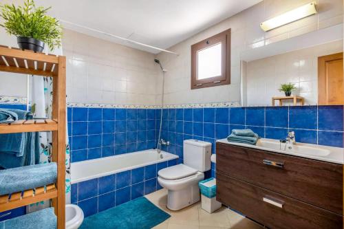 蒂亚斯Modern Duplex in Puerto del Carmen的蓝色的浴室设有卫生间、浴缸和水槽。