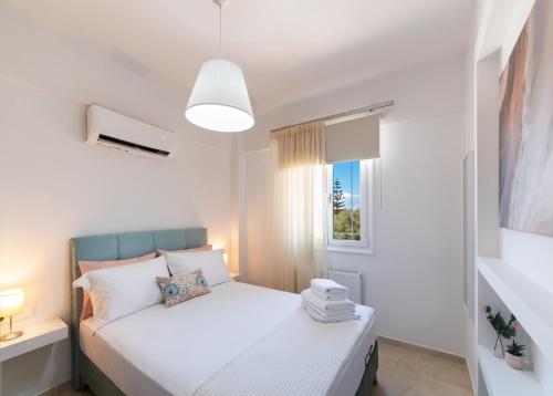 雷夫卡达镇Memoria Apartments by Imagine Lefkada的卧室配有白色的床和窗户。