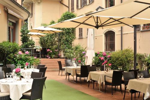 卢加诺联邦酒店的一间带桌椅和遮阳伞的餐厅