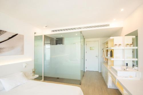 圣安东尼奥湾Els Pins Resort & Spa - Emar Hotels的一间带玻璃淋浴的浴室和一张床
