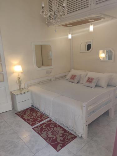 FguraKristu re的白色卧室配有一张白色大床和红色地毯