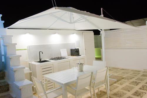加拉蒂纳ArcoSalento的厨房配有桌子和白色遮阳伞