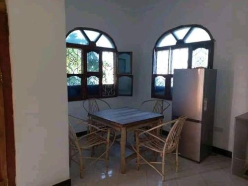 南威Marashi Villa的一间带桌椅和2扇窗户的用餐室