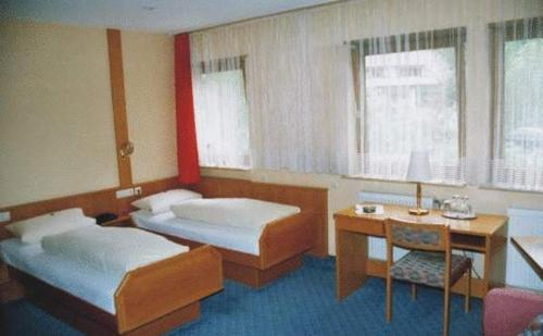 施里斯海姆鲁德威戈斯塔尔酒店的客房设有两张床、一张桌子和一张书桌。