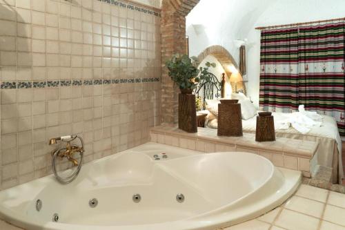 瓜迪克斯阿拉尔孔佩德罗安东尼奥岩洞酒店的配有床的浴室内的白色大浴缸
