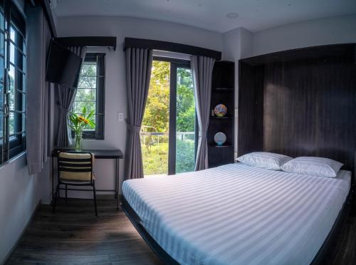 胡志明市Brand New Cozy Home in D1 wBalcony的一间卧室配有一张床、一张书桌和一个窗户。