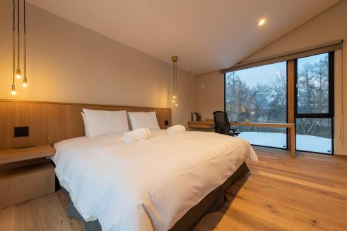 俱知安町Shion的一间卧室设有一张大床和一个大窗户