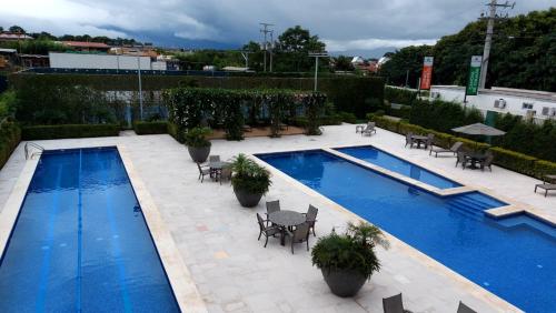 Santo DomingoAltamira Cozy apartment with amazing views的一座带桌椅的游泳池位于酒店大楼旁