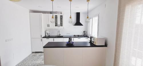 EsteponaCasa Adosada Bel Andalus的厨房配有白色橱柜和黑色台面