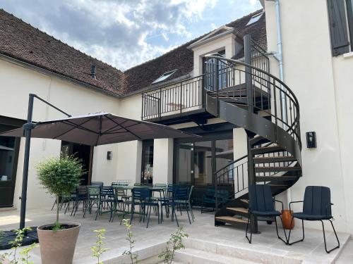 沙布利Appartements Domaine Gueguen Chablis的庭院设有螺旋楼梯和桌椅。