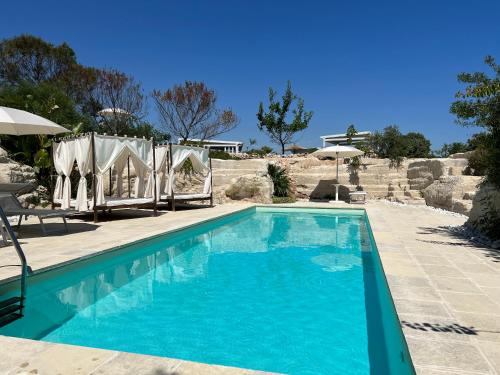 托雷奇安卡Masseria Gelsi的一个带蓝色水和遮阳伞的游泳池