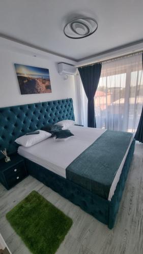 萨图恩Apartament Alina Sunrise的一间卧室配有一张大床和蓝色床头板