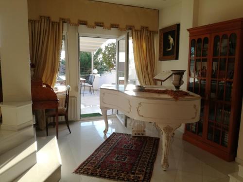 塞萨洛尼基Πολυτελής κατοικία με θέα τον Θερμαϊκό的客厅里设有白色钢琴,设有门廊