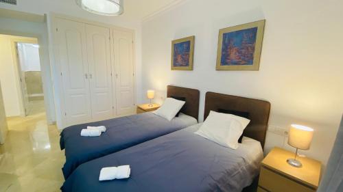 奥亨Marbella Sun Apartment - lush garden and sea view的卧室内的两张床,配有蓝色的床单和白色的枕头