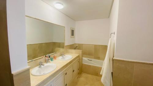 奥亨Marbella Sun Apartment - lush garden and sea view的浴室设有2个水槽、镜子和浴缸。
