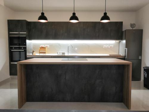 卢加Modern, Spacious, 3 Bedroom Apartment near Malta International Airport的一间厨房,配有黑色橱柜和一个大厨房岛