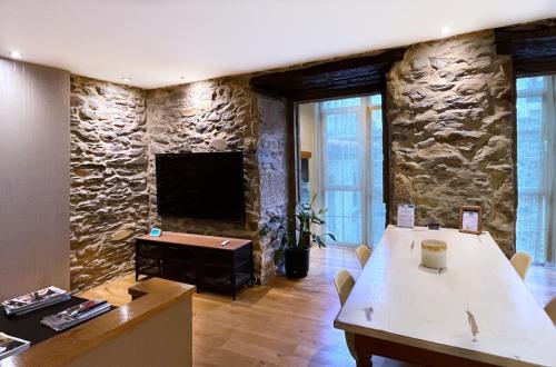维多利亚-加斯特伊兹Luxury Arquillos Vitoria的一间设有石墙、桌子和电视的房间