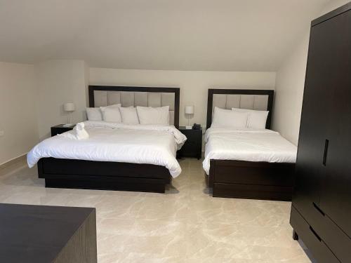 拉马拉Mizirawi Historic Hotel的一间卧室配有两张带白色床单的床