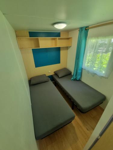 Saint-ChéronMobil-home 6 personnes climatisé le Miami的小房间设有两张床和窗户