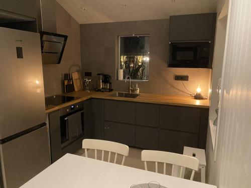 耶尔夫瑟Ekberg Annexet的厨房配有黑色橱柜和白色的桌椅