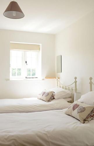 林德赫斯特Mill Lane Farm Holiday Cottages的白色客房的两张床,设有窗户