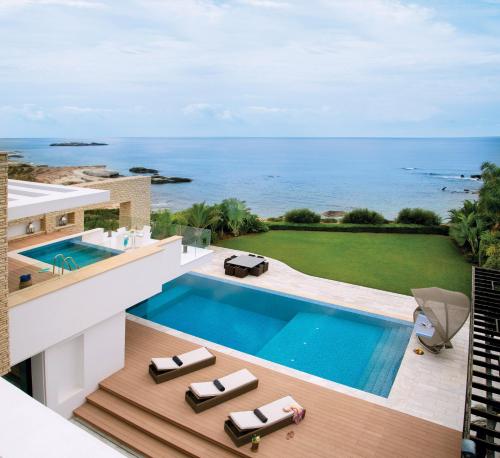 佩亚Cap St Georges Villas的享有带游泳池和大海的房屋的空中景致