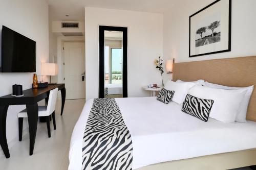 马里纳-迪-皮特拉桑塔蒙迪艾尔度假温泉酒店的卧室配有一张白色大床、书桌和电视。