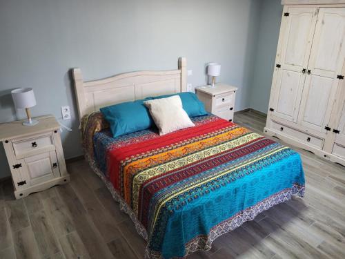 奇克拉纳－德拉弗龙特拉ZARAPITO的一间卧室配有一张带彩色毯子和2个床头柜的床