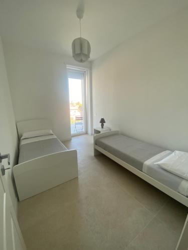 萨莱诺Carlino's Home的白色的客房设有两张床和窗户。