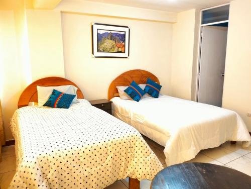 库斯科Hostal Ukumari Andino的酒店客房设有两张床和一张桌子。